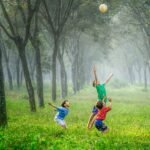 four boy playing ball on green grass